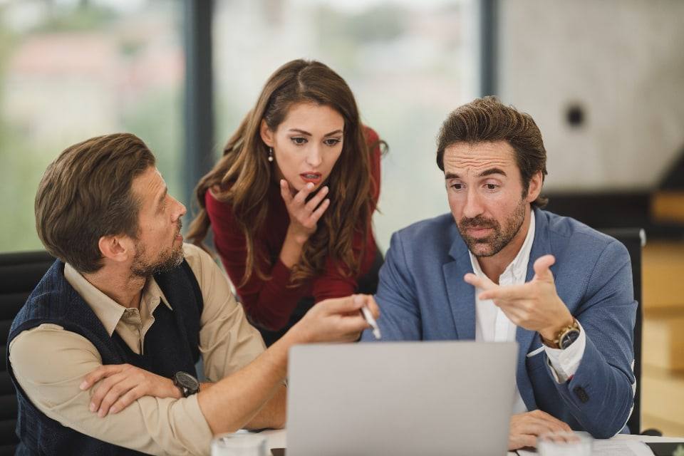 Tre kolegë diskutojnë rreth një laptopi